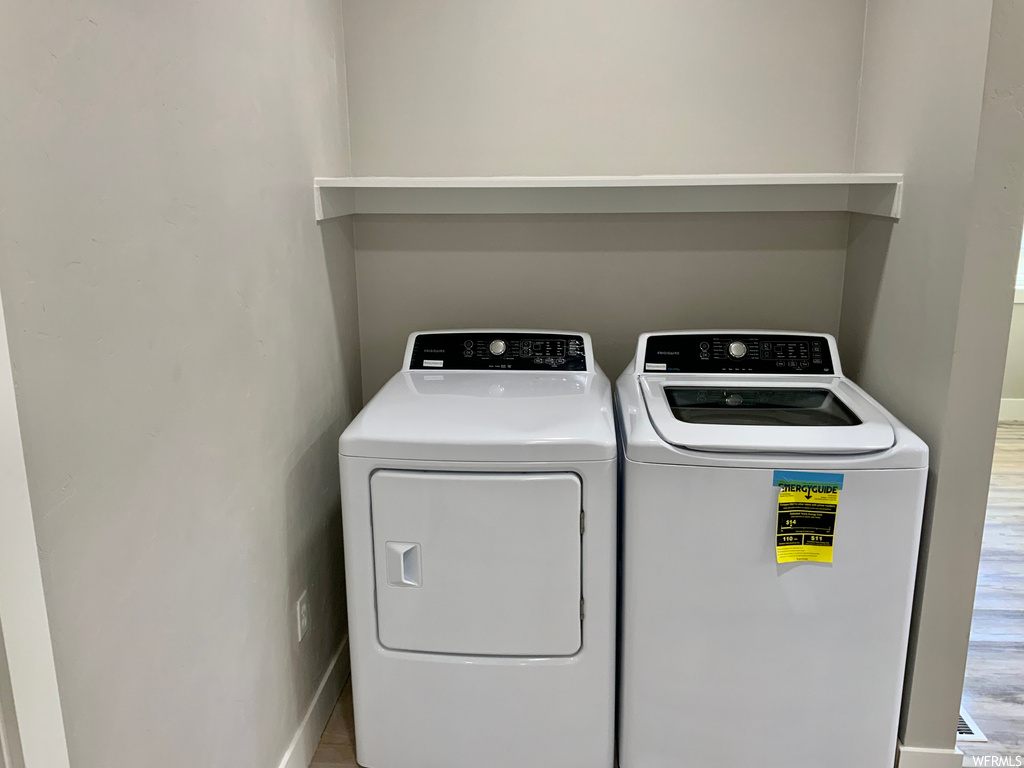 Laundry area with separate washer and dryer and light hardwood flooring