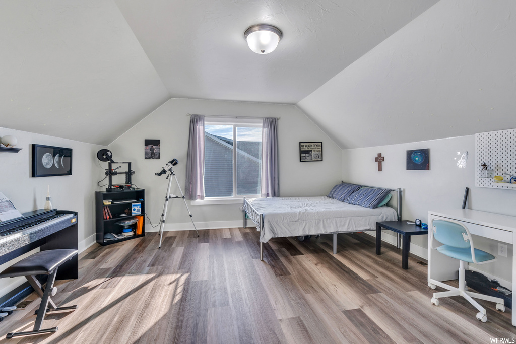 Bedroom with hardwood flooring and vaulted ceiling