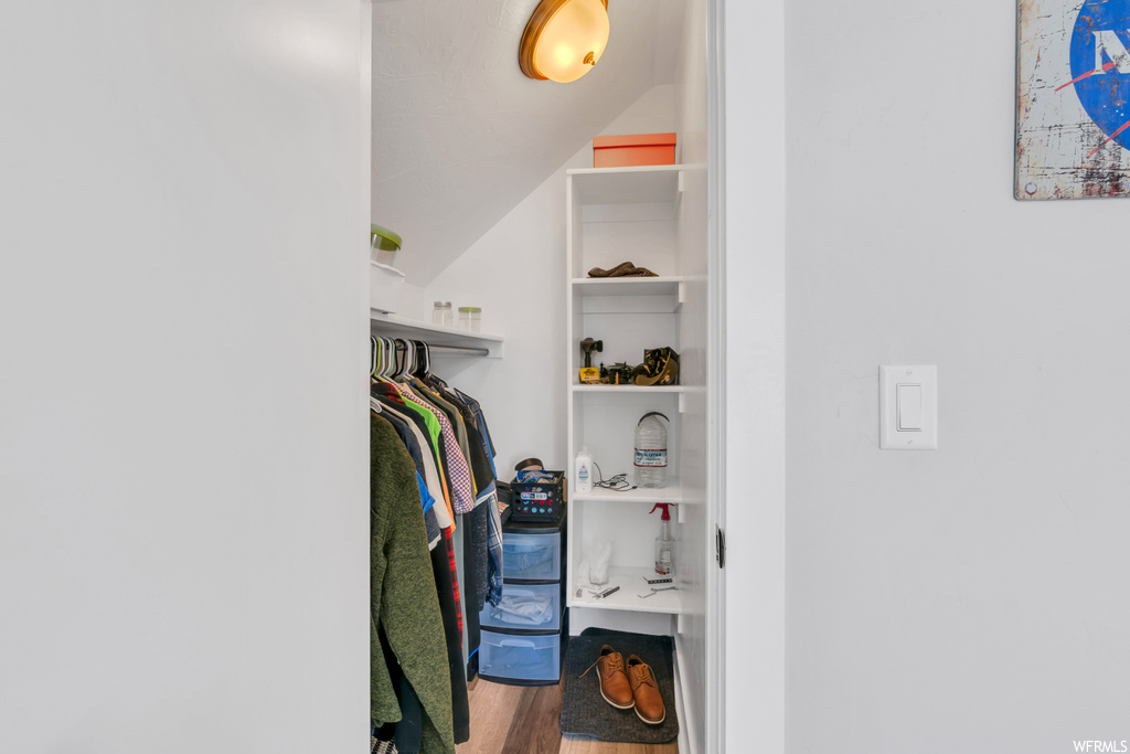 Walk in closet with vaulted ceiling and hardwood floors