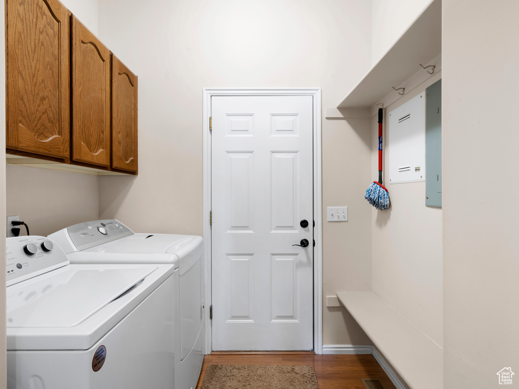 Clothes washing area with independent washer and dryer, cabinets, and hardwood / wood-style floors