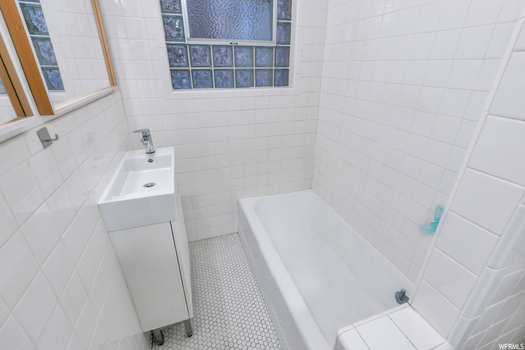 Bathroom featuring sink, tile walls, tiled shower / bath, and tile flooring
