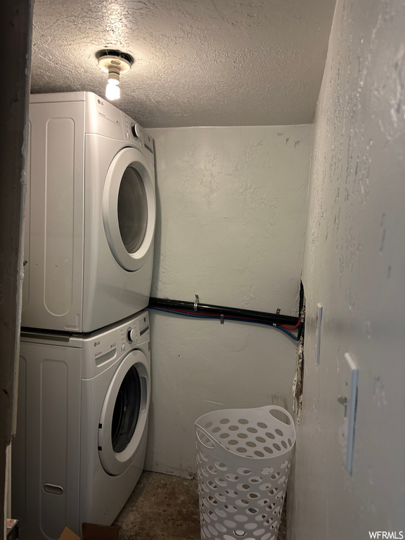Laundry area featuring a textured ceiling and stacked washer / drying machine