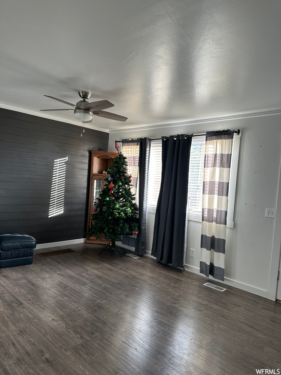 Unfurnished room featuring a healthy amount of sunlight, crown molding, dark hardwood floors, and ceiling fan