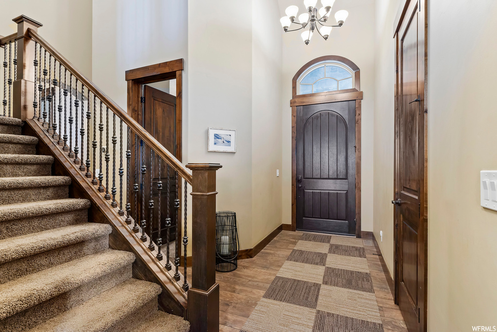 Hardwood floored foyer featuring a towering ceiling and a notable chandelier