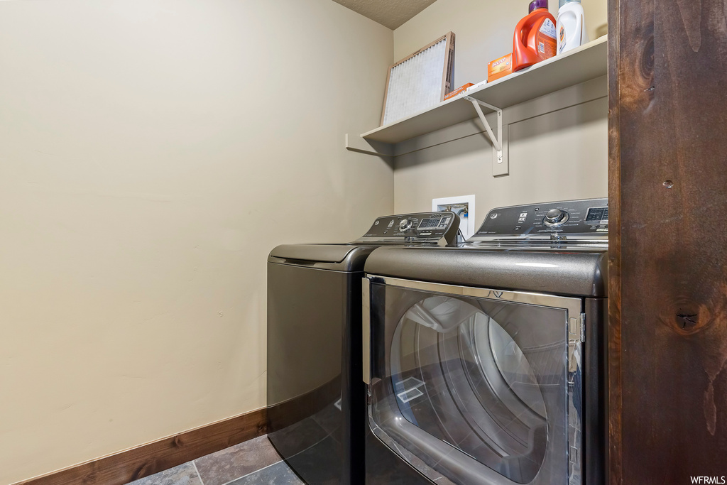 Washroom featuring independent washer and dryer, dark tile floors, and washer hookup