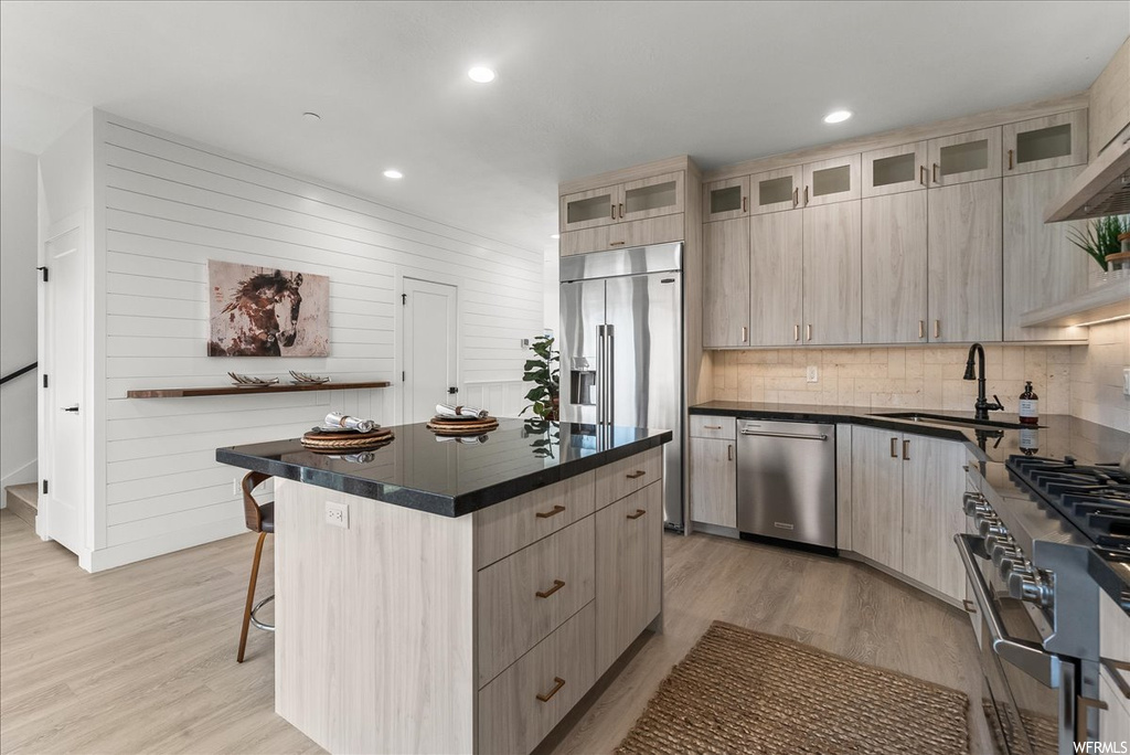 Kitchen featuring a center island, sink, premium appliances, and light hardwood floors