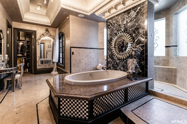 Bathroom featuring a tray ceiling, shower with separate bathtub, vanity, crown molding, and tile floors