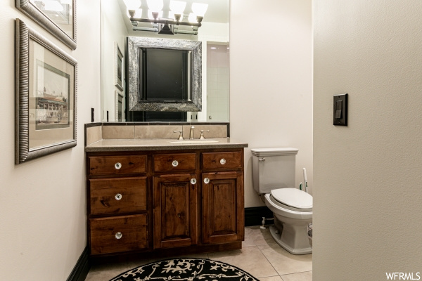 Bathroom featuring an inviting chandelier, vanity, tile floors, and toilet