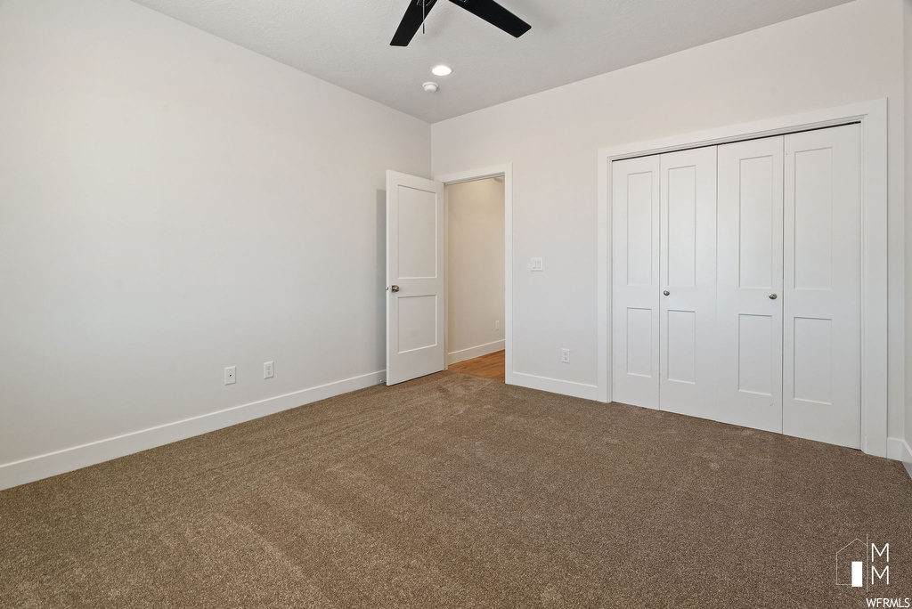 Unfurnished bedroom with ceiling fan, a closet, and carpet floors