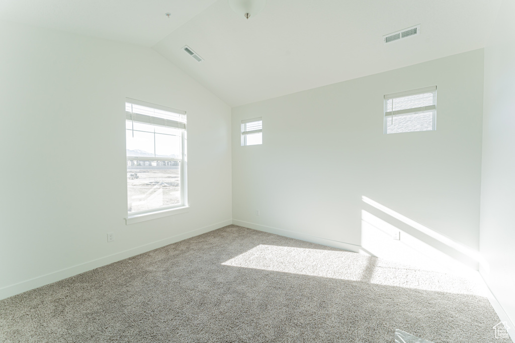 Unfurnished room featuring light carpet and lofted ceiling