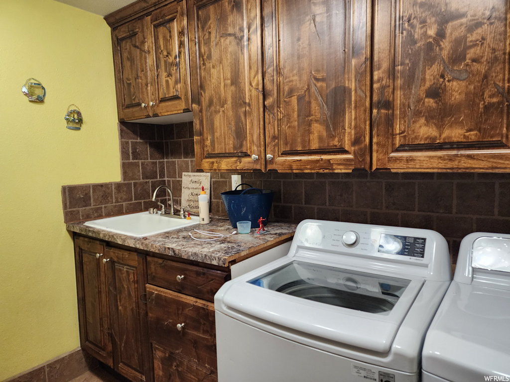 Laundry room with sink, independent washer and dryer, and cabinets