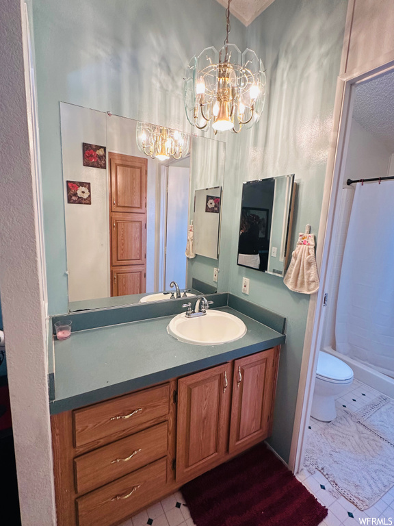 Bathroom featuring tile flooring, toilet, large vanity, and a chandelier