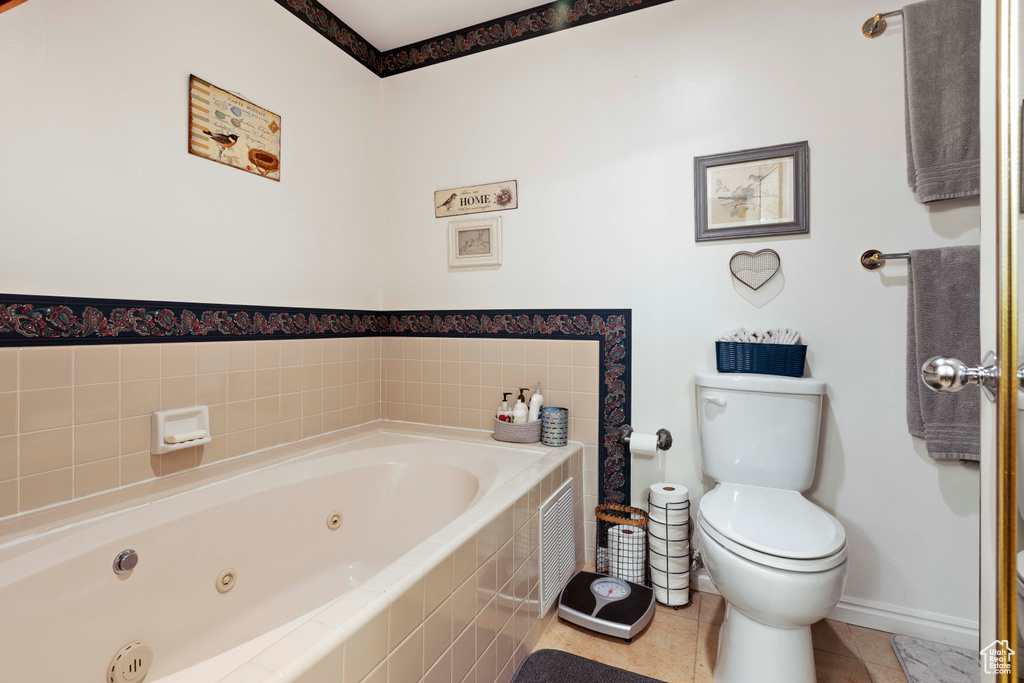 Bathroom with a relaxing tiled bath, tile floors, and toilet