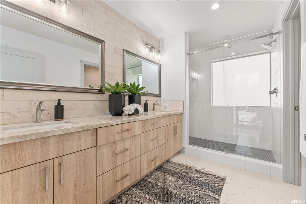 Bathroom featuring tile flooring, large vanity, dual sinks, and backsplash