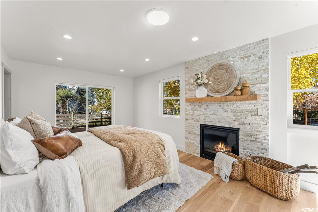Bedroom featuring access to exterior, a fireplace, and light hardwood / wood-style flooring