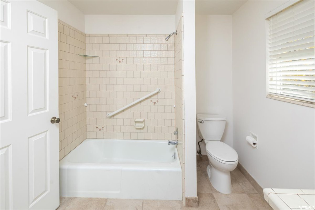 Bathroom with tile floors, toilet, and tiled shower / bath combo