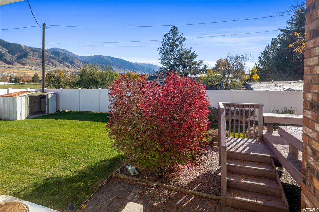 View of yard featuring a storage shed and a deck with mountain view