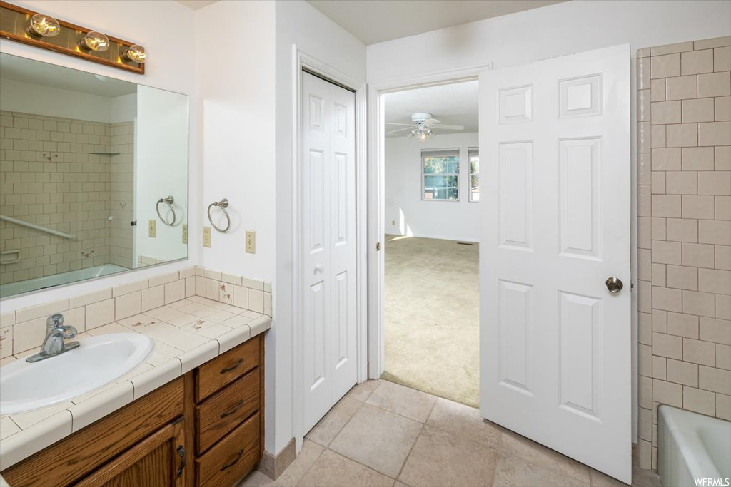 Bathroom featuring tile flooring, ceiling fan, tub / shower combination, and vanity