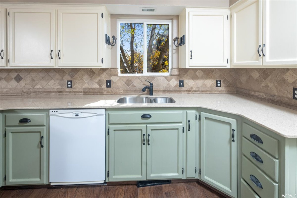Kitchen with dark wood-type flooring, sink, backsplash, white cabinets, and white dishwasher