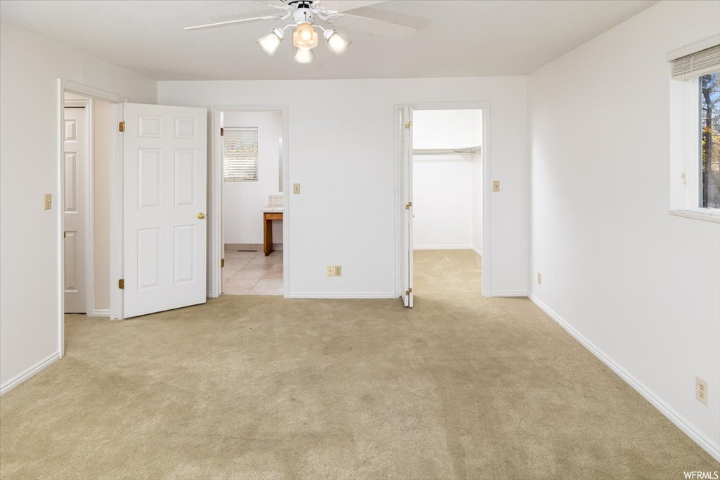 Empty room featuring ceiling fan and light carpet
