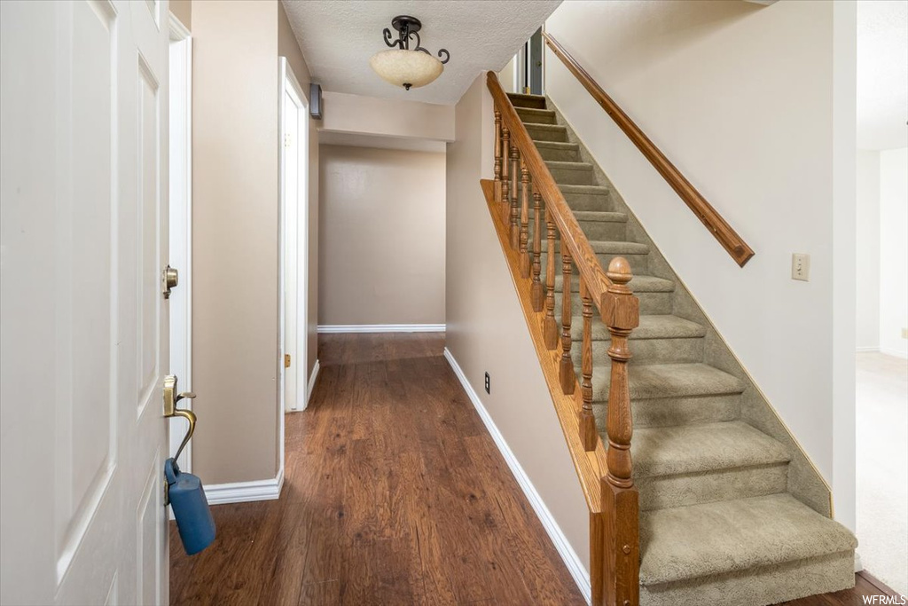 Stairway featuring a textured ceiling and dark hardwood / wood-style floors