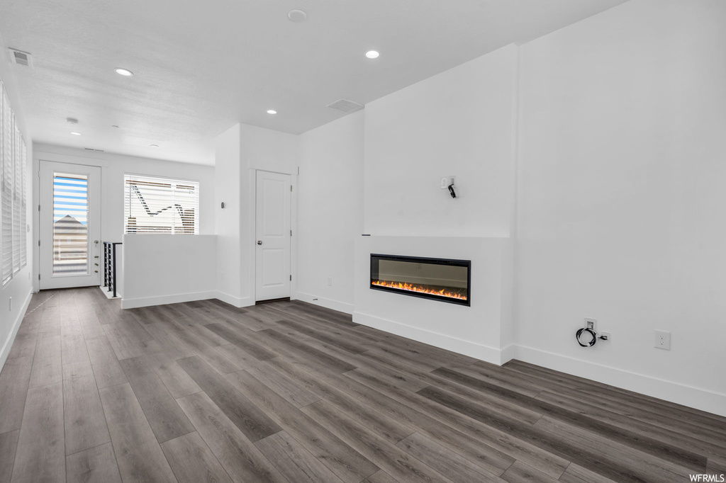 Unfurnished living room featuring a fireplace and dark hardwood floors