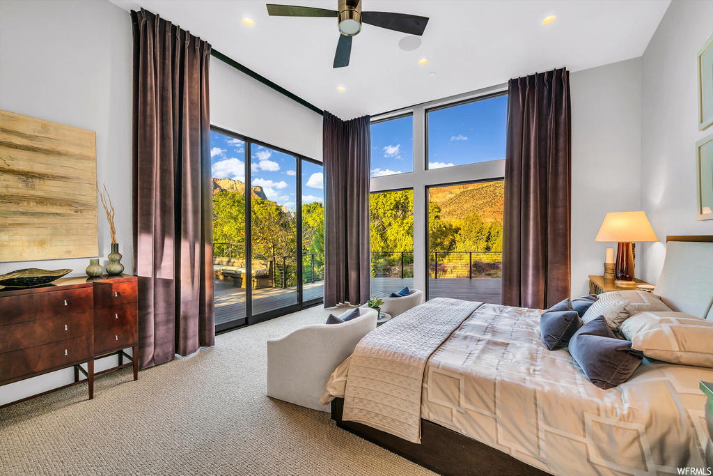 Bedroom featuring light colored carpet, ceiling fan, expansive windows, and access to outside