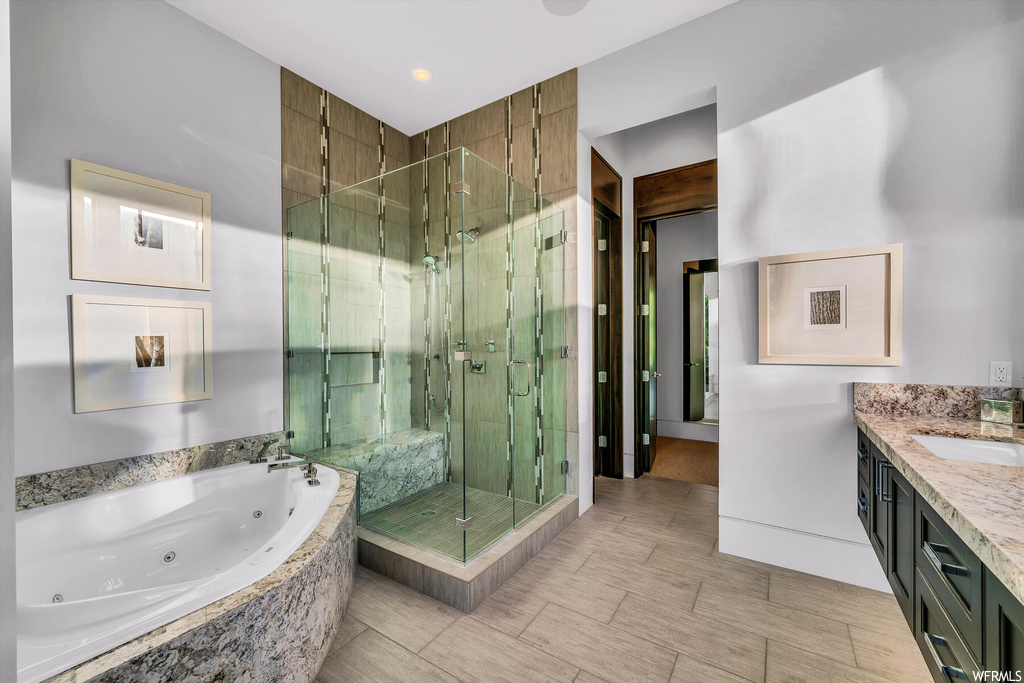 Bathroom featuring tile flooring, shower with separate bathtub, and vanity