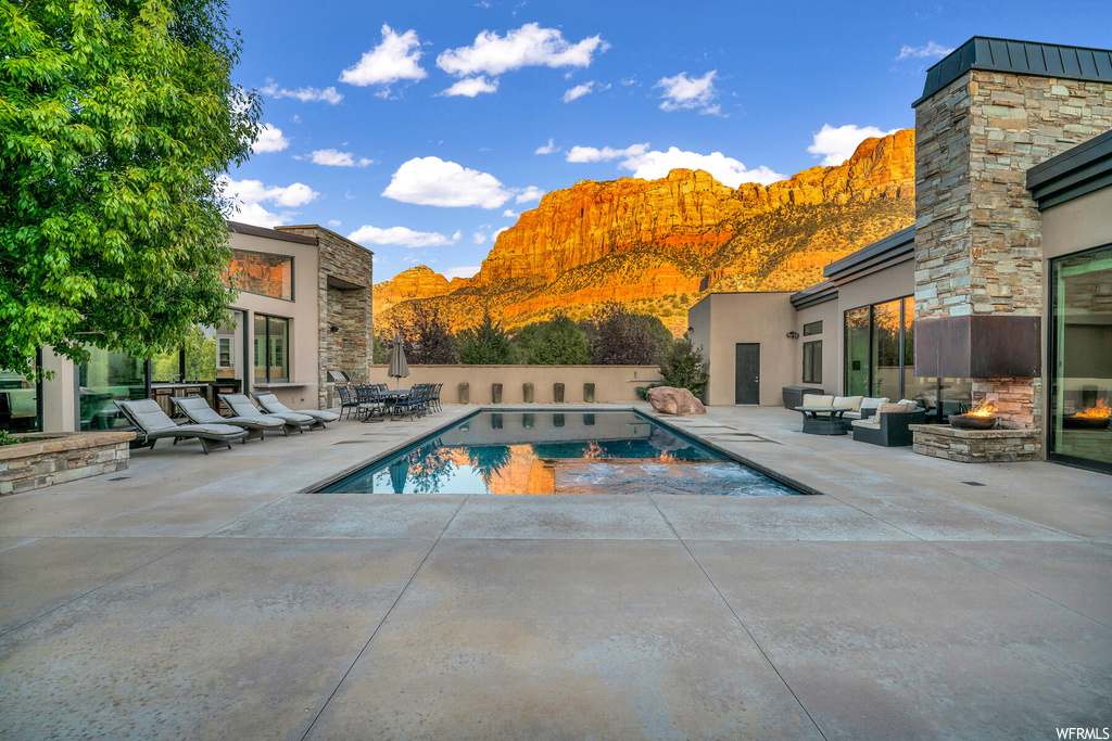 View of swimming pool featuring a patio area, an outdoor living space with a fire pit, and a mountain view