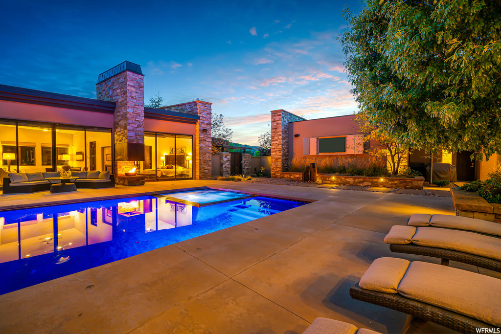 Pool at dusk featuring outdoor lounge area and a patio