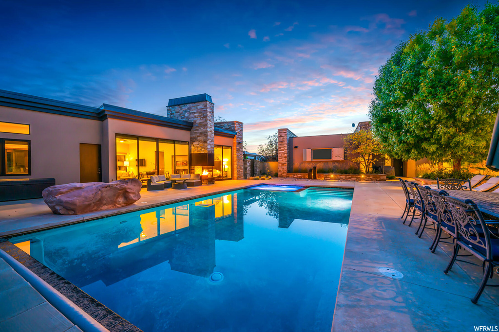 Pool at dusk with a patio area and an outdoor living space