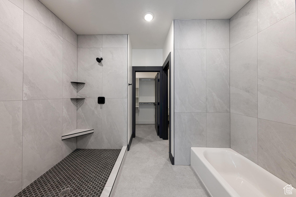 Bathroom with tile walls, tiled shower, and tile flooring
