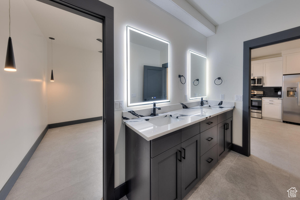Bathroom with double sink, tile floors, vanity with extensive cabinet space, and tasteful backsplash