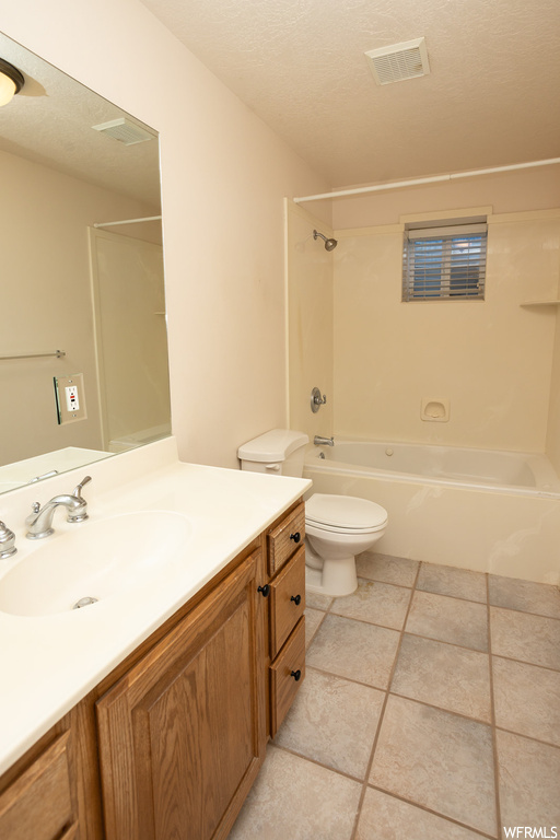 Full bathroom featuring tile flooring, a textured ceiling, toilet, vanity with extensive cabinet space, and tub / shower combination