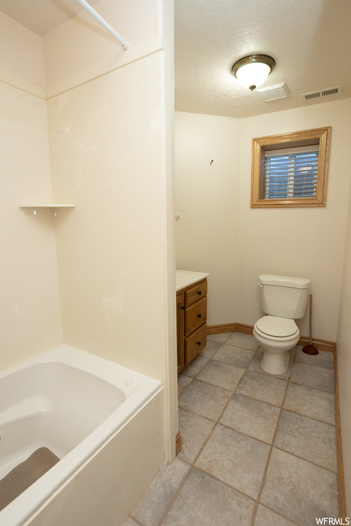 Full bathroom featuring vanity, tile flooring, a textured ceiling, toilet, and tub / shower combination