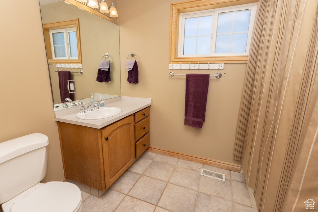 Bathroom with tile flooring, toilet, and vanity with extensive cabinet space