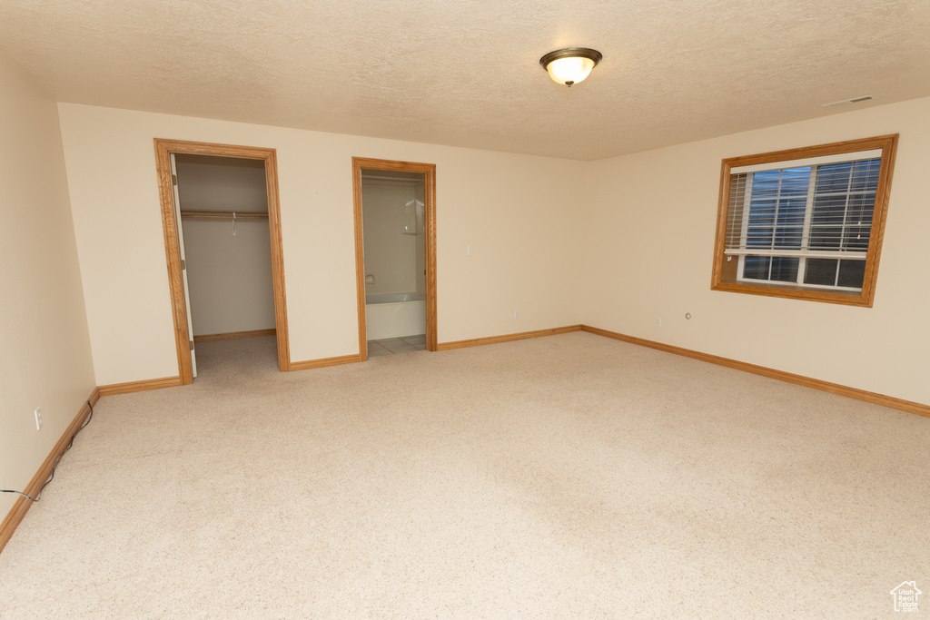 Unfurnished bedroom featuring carpet, a closet, a textured ceiling, and a spacious closet