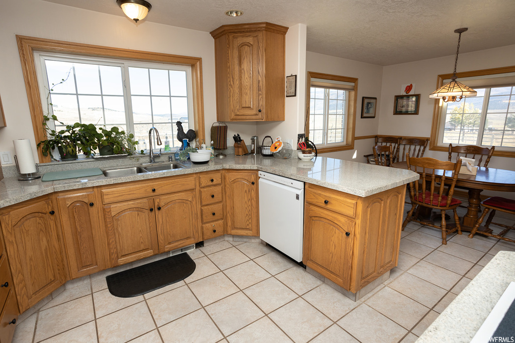 Kitchen featuring sink, decorative light fixtures, dishwasher, and light tile floors