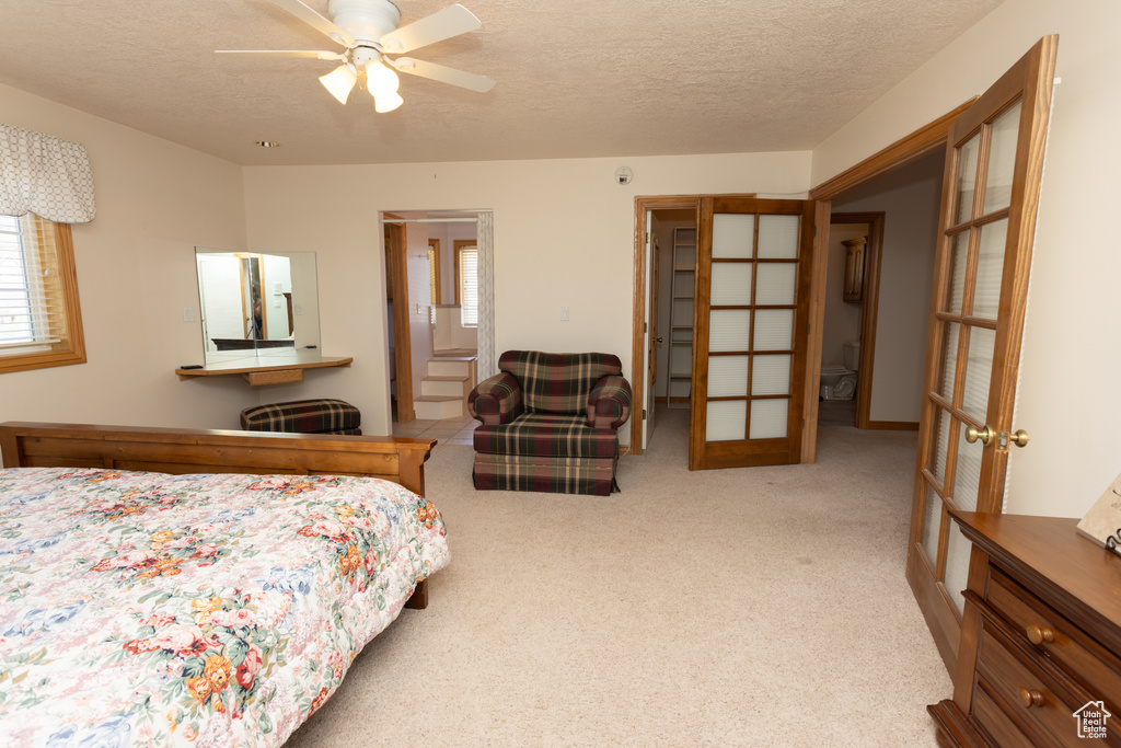 Bedroom featuring ceiling fan, multiple windows, a textured ceiling, and carpet flooring