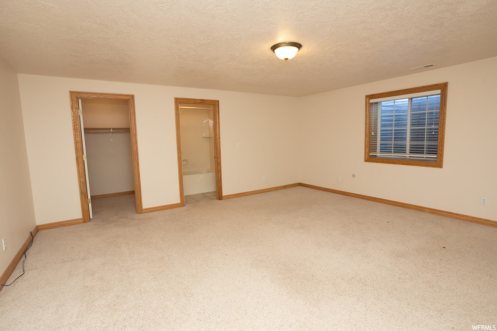 Unfurnished bedroom with a textured ceiling, a closet, and light colored carpet