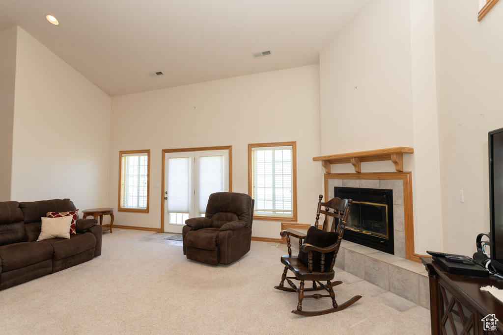 Living room featuring high vaulted ceiling, a tile fireplace, and carpet flooring