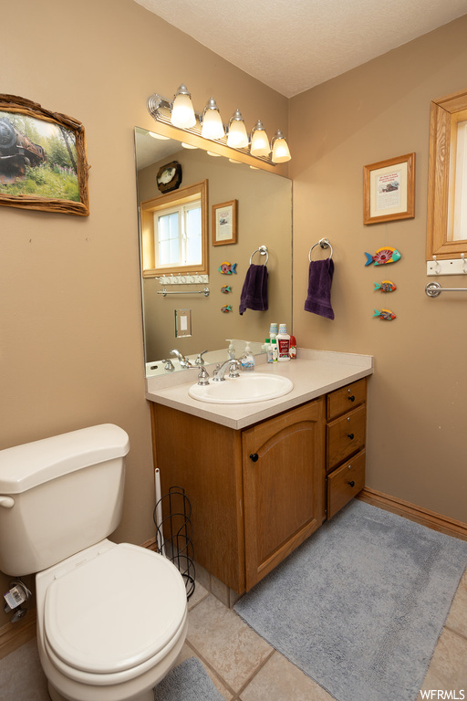 Bathroom featuring tile flooring, a textured ceiling, toilet, and vanity