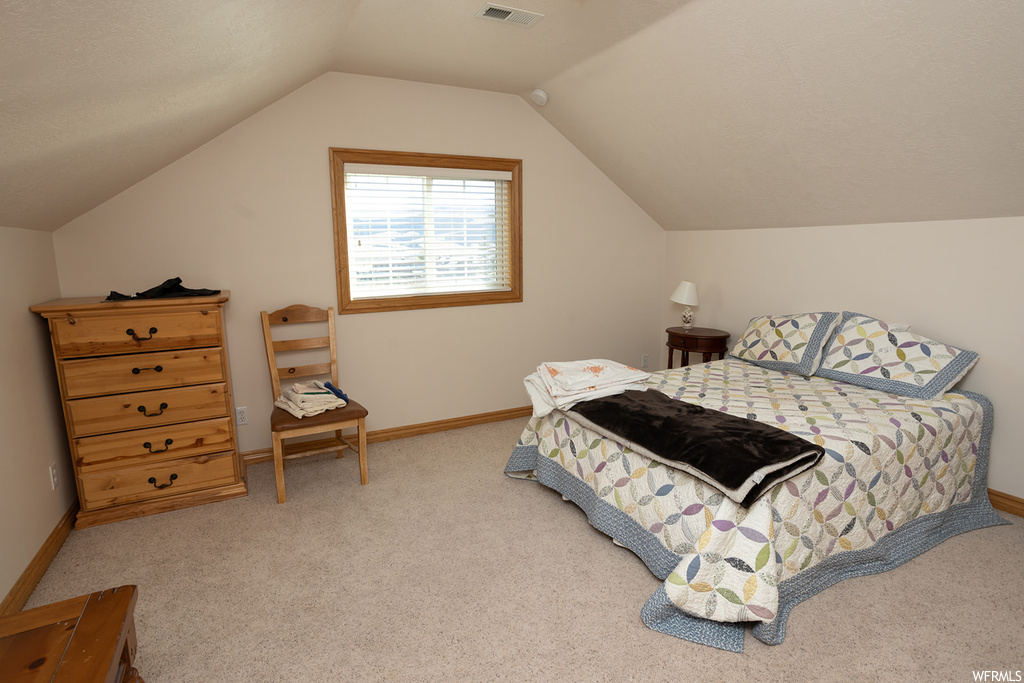 Bedroom featuring light colored carpet and lofted ceiling