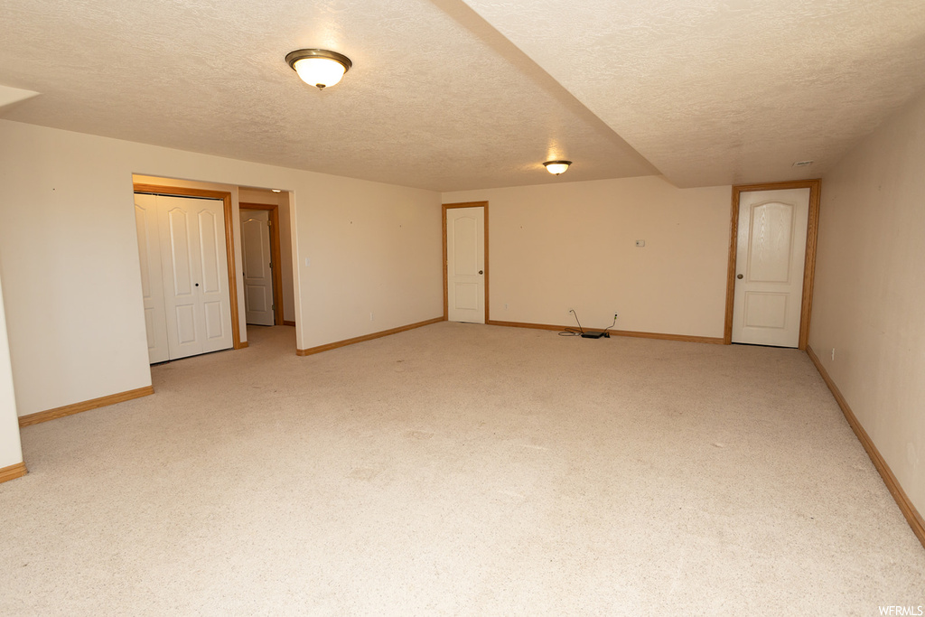 Unfurnished room with a textured ceiling and light colored carpet