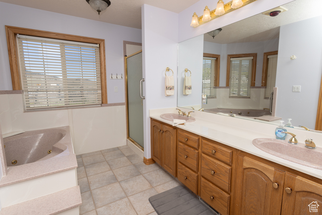 Bathroom with tile floors, independent shower and bath, and double sink vanity