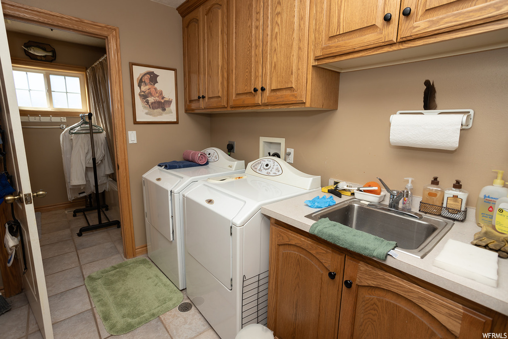 Clothes washing area featuring independent washer and dryer, sink, light tile floors, cabinets, and hookup for a washing machine