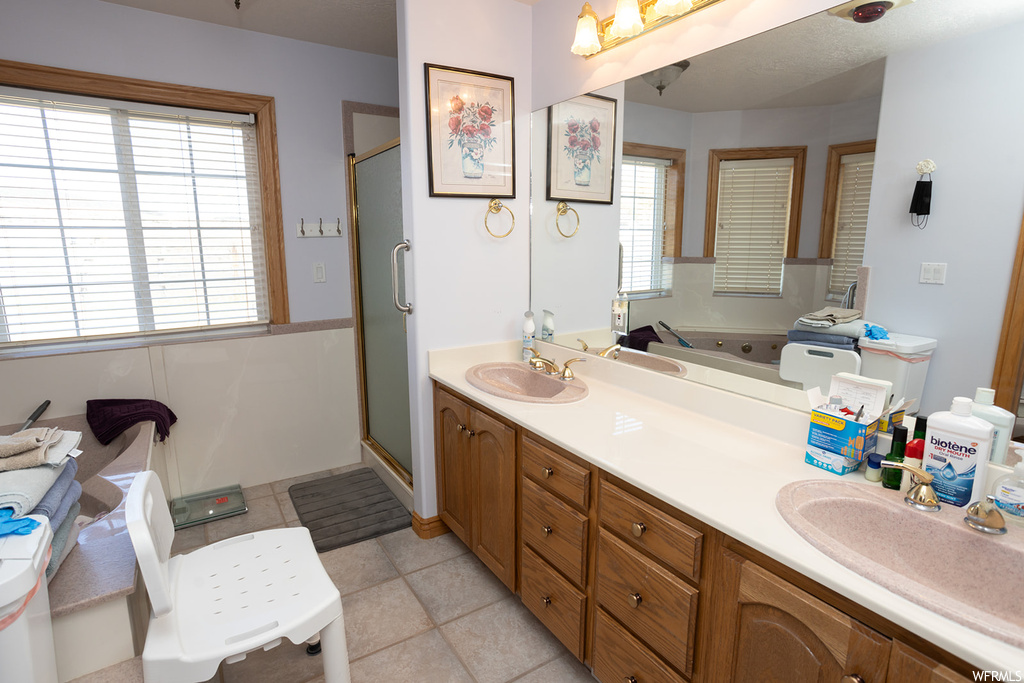 Bathroom featuring tile flooring, dual sinks, separate shower and tub, and vanity with extensive cabinet space