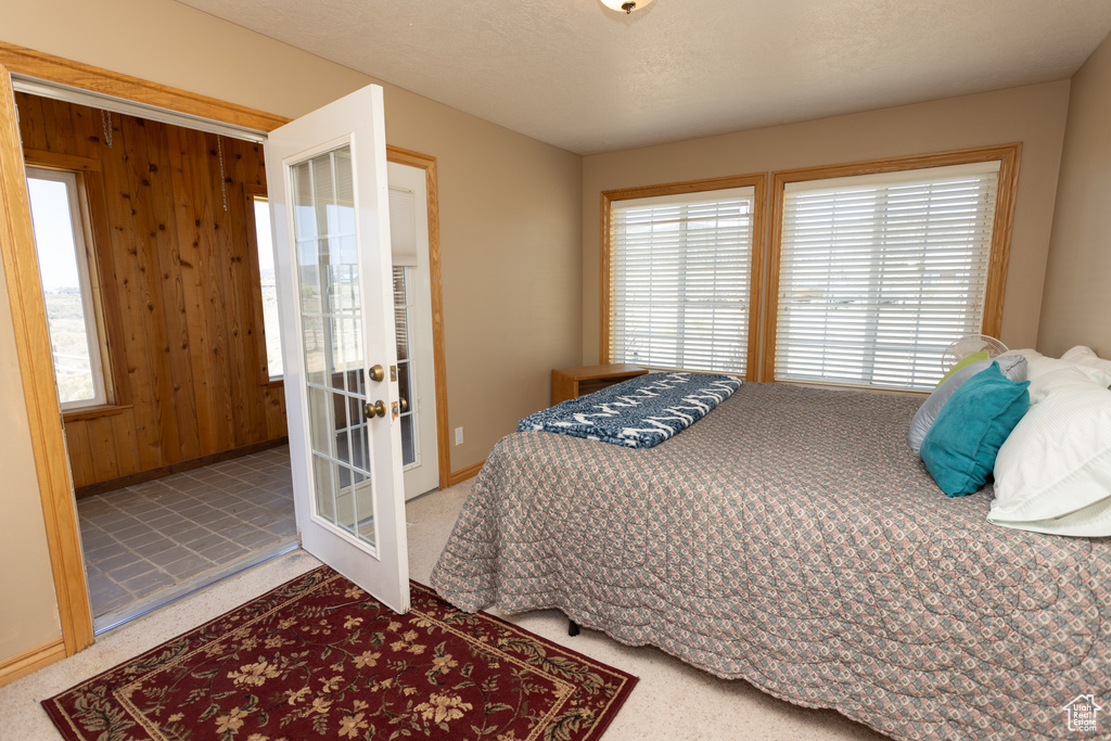 Tiled bedroom with wooden walls, multiple windows, and french doors