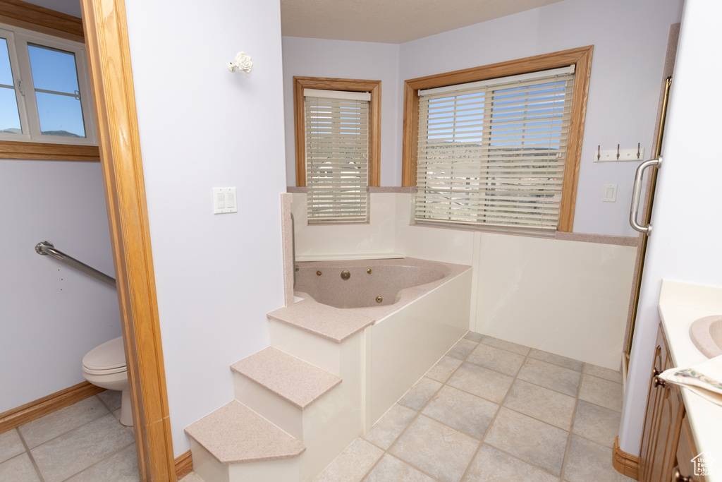 Bathroom featuring tile floors, a washtub, vanity, and toilet