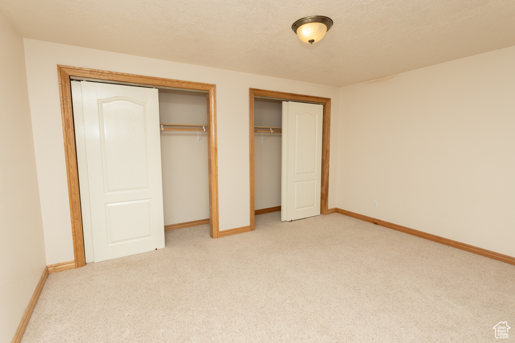 Unfurnished bedroom featuring carpet and two closets